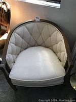 Front view of one vintage barrel-back armchair showing tufted backrest, cushioned seat, and wood framing.