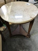 Side view of round marble top table showing wood base and legs