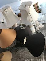 Five table lamps of different styles arranged on a surface under bright lighting showing shades and bases