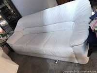 Full view of the bone white leather couch showing three seats, padded armrests, and slight soiling. Couch appears used with some wear but intact.