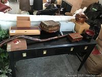 Full view of the lot including black table with various wooden boxes, bowls, and a long rustic walking stick.