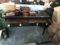 Black wooden sofa table showing one large drawer open with four square brass handles, some scratches and chips visible