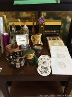 Photo showing assorted decorative items including stein, glass horse figurine, various bowls, vases, small figurines, and sets of coasters and plates