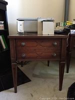 Two wooden side tables stacked with camera, phone, and other items on top