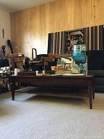 Full view of the large wooden coffee table with items on top showing its dark wood finish and lower shelf.
