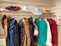 Top shelf view showing 4 straw hats; lower rod view showing fur stole and assorted coats.