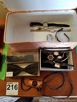 Full lot overview showing two boxes with multiple watches inside and bow ties displayed around them.