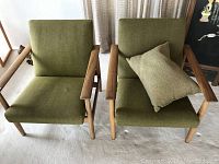 Front view showing both chairs with wooden arms and green upholstery