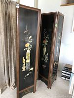 Full view of the four-panel folding screen showing hand-painted floral and vase designs on black panels with wooden frame.