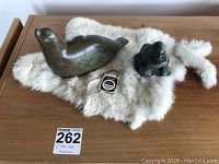 Both jade seal and dark stone man figurines displayed on a white fur rug.