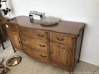 Full view of the wooden Knechtel sideboard showing curved front, drawers, and cabinet doors.