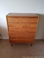 Front view of teak dresser showing six drawers and tapered legs