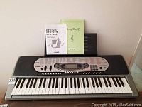 Full view of Casio CTK 573 keyboard with user manual and song book placed on the music stand.