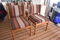 Four teak wood dining chairs in a room with matching upholstery and teak frames