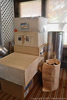 Stack of cardboard boxes and a paper bag containing Sunscope system parts