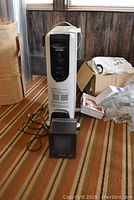 Pelonis oil filled heater in upright position with black control panel and dial, placed on carpet.
