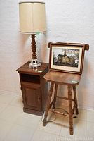 Photo showing bar stool, telephone table with lamp on top, and framed photo on stool