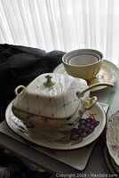 View of soup tureen, ladle, platters and nested bowls showing detailed decoration and condition
