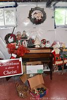 Overview of lot on piano bench: wreath, red sign, wooden cutouts, ceramic tree, mug, ribbons, boxes