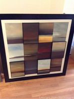 Front view of large framed abstract wall art print composed of nine rectangular panels with gradient earth tone colors showing horizontal landscape-like shading.