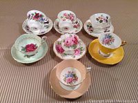 Top view of all seven cups and saucers showing varied floral patterns and colors.