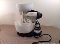 Side view of the Sunbeam Mixmaster showing two white mixing bowls and chrome beaters installed.
