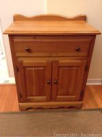 Front view of the wooden washstand showing drawer and cabinet doors.
