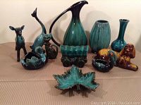 Full layout of all 11 pottery pieces showing ewer jug, covered wagon piggy bank, leaf dish, various animal figurines and vases.