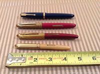Four vintage fountain pens lined up horizontally on striped cloth with measuring tape indicating length between 4 and 5 inches