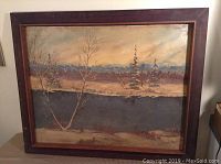 Full view of the framed Gordon Eugene Baker oil painting showing a river scene with trees and hills in the background, with visible wear and dirt.