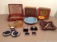 Full lot arranged on a table showing tobacco tins, cigar box, ashtrays, and lighters.