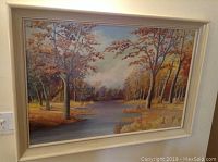 Front view of framed oil painting showing river flowing through autumn forest