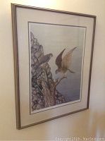 Framed artwork showing two ospreys near rocks, one perched and one flying, inside a silver-toned frame.