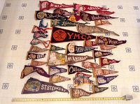 Overview of all vintage pennants laid out flat on a tiled floor showing variety of colors, designs and sizes from USA and Canada.