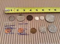 Top-view photo showing the nine coins arranged in a line with a tape measure for size reference