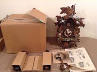 Full view of cuckoo clock, original box, two boxed parts, coiled spring, pendulum leaf, and instruction sheet.