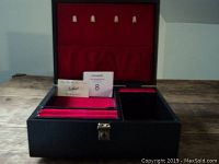 Open jewelry music box showing red velvet interior with ring holders and compartments, plus Tallent brand card and auction lot number card inside.