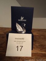 Swarovski crystal swan on top of the dark blue Swarovski box with auction lot number in front.