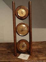 Full view of the three dial barometer set on wooden frame, showing top, middle and bottom dials.