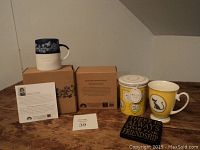 Yellow ceramic tea cup mug with black cat silhouette and Maxwell Williams canister with heart design, with their boxes and pricing card.
