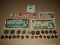 Lot includes vintage Canadian one-dollar bills, four Calgary casino chips, Indonesian banknote, and assorted Canadian coins arranged on carpet.