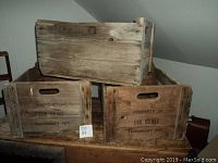 Photo showing three stacked wooden apple crates with stamped markings for Earl Holmes farm and Thornbury Ont. The top crate is unmarked wood.