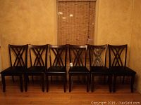 Full set of six solid wood dining chairs arranged in a row showing their uniform design and condition.