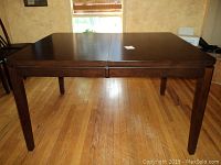 Front view of dining table with extension leaf removed, showing 54" length and 42" width on wooden floor.