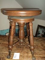 Front and side view of wooden piano stool with claw feet and round adjustable seat