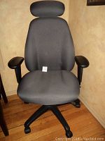 Front view of the dark gray executive office chair showing headrest, padded seat, and armrests.