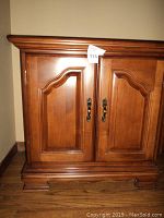 Front view of solid mahogany nightstand with two panelled doors and brass-toned handles