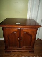 Front view of solid mahogany night stand showing two paneled doors with brass handles and polished top surface.