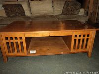 Front view of the solid oak Mission style coffee table showing vertical slat side panels and open shelf.