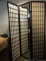 Privacy screen standing partially folded in a room, showing all 3 panels including the one with a framed mirror.